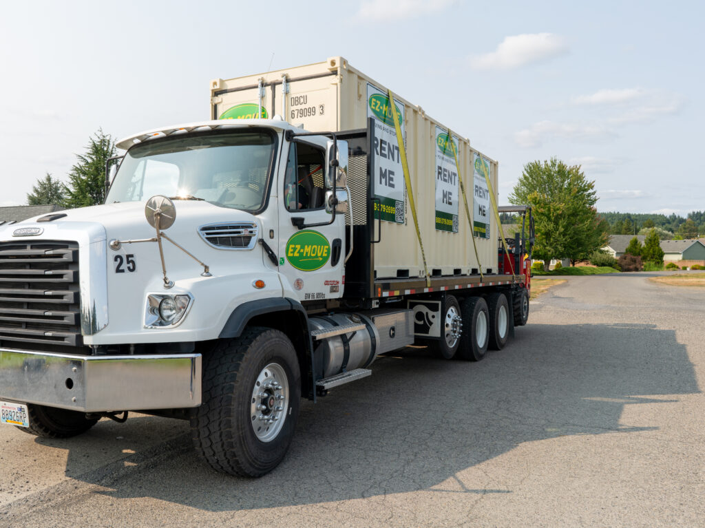 A white EZ Move truck hauling three moving containers.